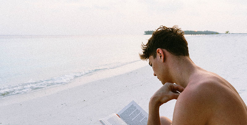 chico leyendo libro en la playa