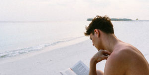 chico leyendo un libro en la playa